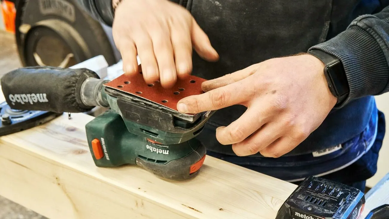 Handwerker bringt das Multiloch-Schleifpapier auf.